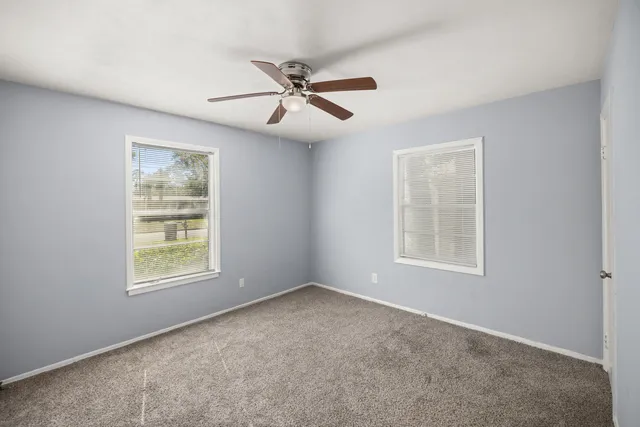 an empty room with windows and fan
