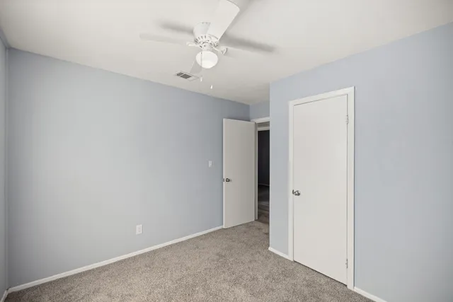 an empty room with a ceiling fan and a window