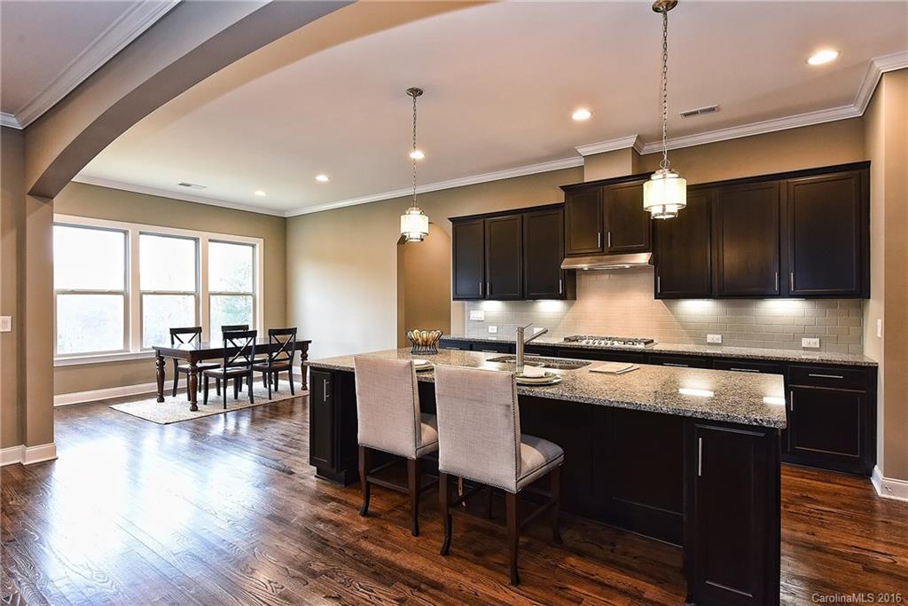 8069 Clems Branch Road Indian Land, SC 29707 - Photo 9 of 24 a kitchen with stainless steel appliances granite countertop a stove top oven a refrigerator a dining table and chairs with wooden floor