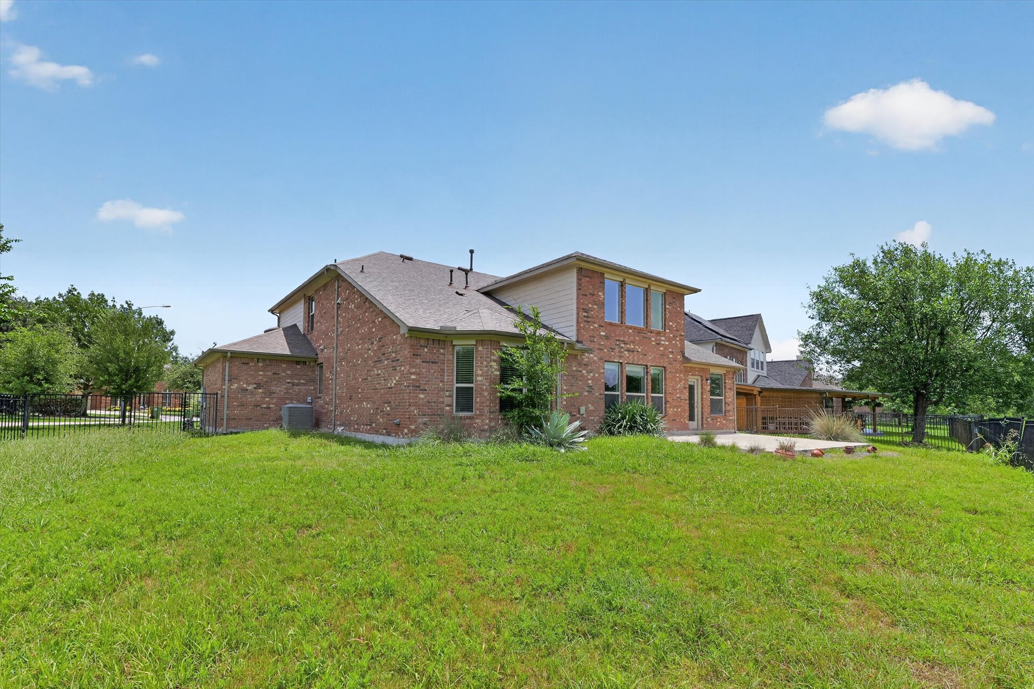 11306 Runnel Ridge Road Manor, TX 78653 - Photo 15 of 18 A well-maintained lawn stretches behind a brick-clad residence, featuring a covered patio for outdoor enjoyment.