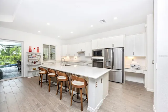 a kitchen with stainless steel appliances a white table chairs and a refrigerator