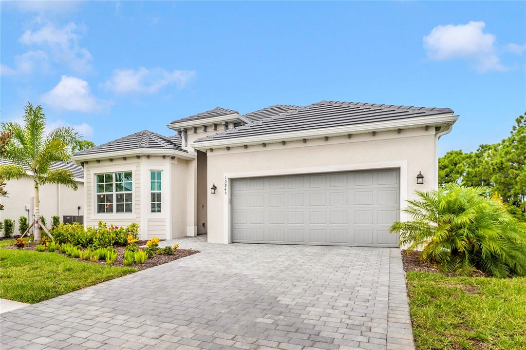 12845 Tulum Loop Venice, FL 34293 - Photo 55 of 100 a front view of a house with a garden and garage