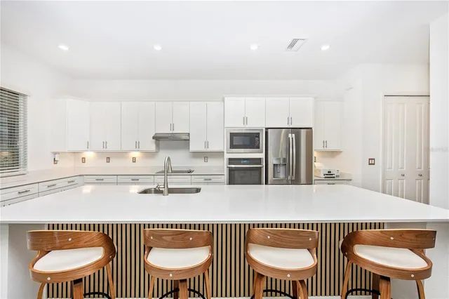 a kitchen with stainless steel appliances granite countertop a sink a stove and a refrigerator