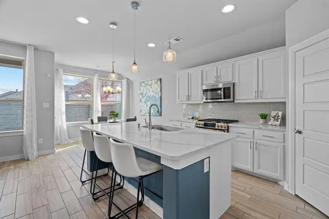 a kitchen with kitchen island granite countertop a sink a stove a refrigerator cabinets and dining table