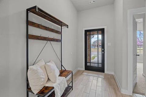 a view of a hallway that has a couch and a dining table with wooden floor
