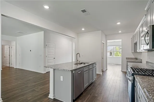 a kitchen with stainless steel appliances granite countertop a lot of counter space and wooden floors