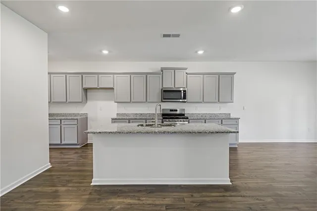 a kitchen with stainless steel appliances granite countertop a stove a sink and a microwave