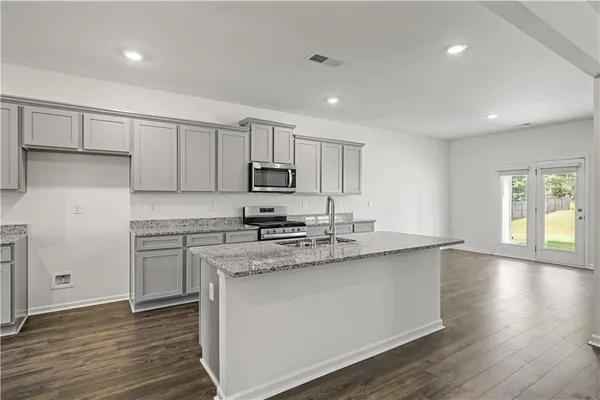 a kitchen with stainless steel appliances granite countertop a stove a sink and white cabinets