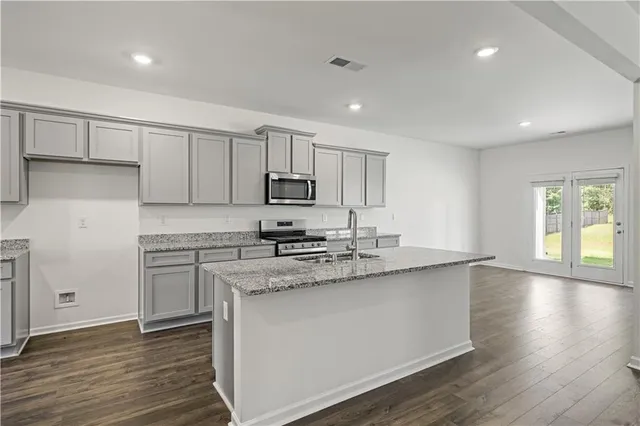 a kitchen with stainless steel appliances granite countertop a stove a sink and white cabinets