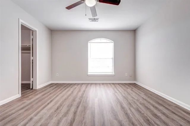 an empty room with wooden floor cabinet and windows