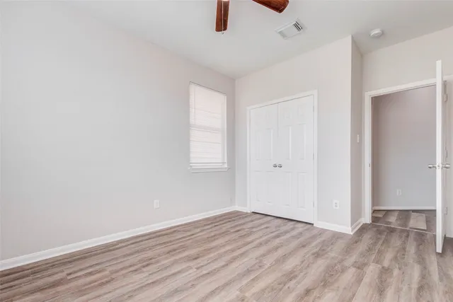 an empty room with wooden floor cabinet and windows