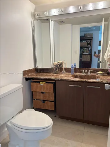 a bathroom with a granite countertop toilet sink and mirror