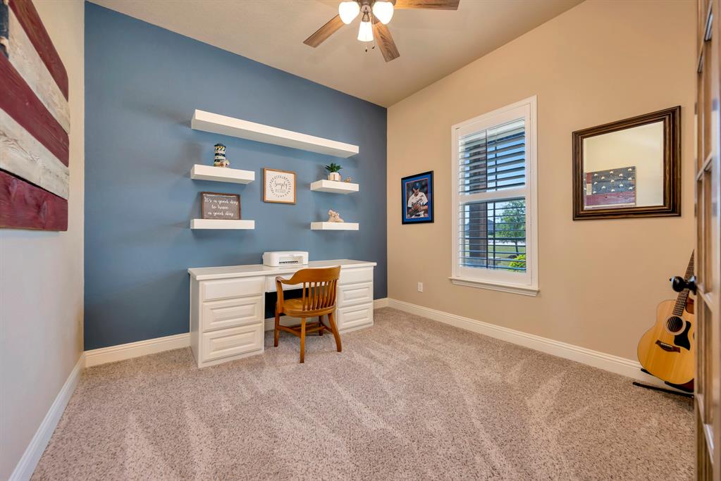 3224 North Cardinal Road Azle, TX 76020 - Photo 10 of 40 Dedicated office space, recently installed carpeted flooring, a built-in white desk with drawers, white floating wall shelves, a window with louvered shutters, and a ceiling fan with integrated lighting