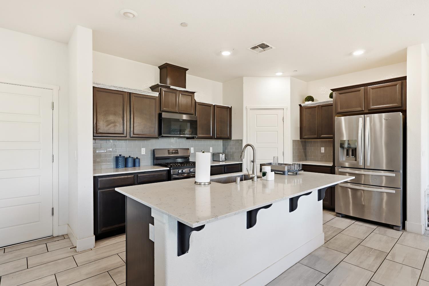 2367 Explorador Drive Merced, CA 95340 - Photo 14 of 42 a kitchen with stainless steel appliances a sink stove refrigerator and cabinets