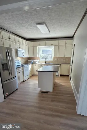 a large kitchen with kitchen island a large counter top space a sink stainless steel appliances and cabinets