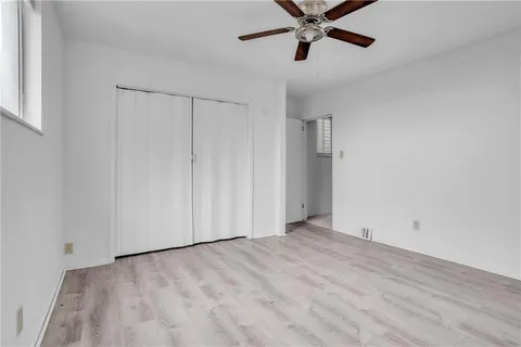 an empty room with a ceiling fan and windows