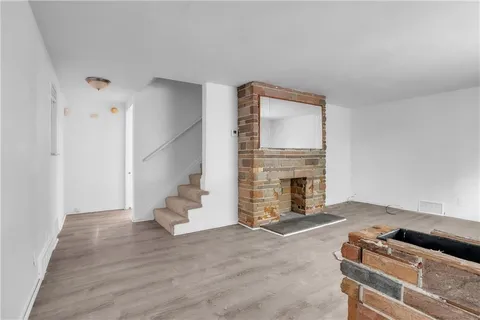 a view of an empty room with wooden floor and a fireplace