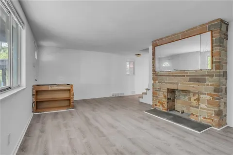 a view of an empty room with fire place and a window