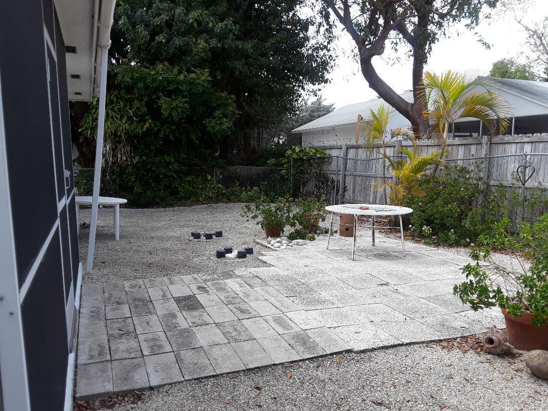 14 Jewfish Avenue Key Largo, FL 33037 - Photo 30 of 44 a backyard of a house with table and chairs under an umbrella