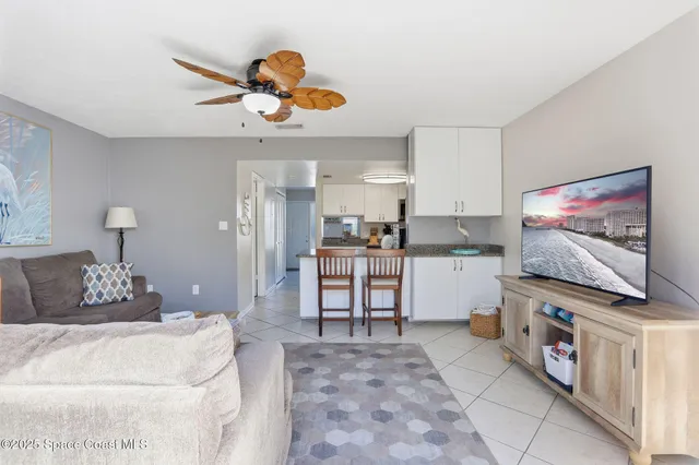 a living room with furniture and a flat screen tv with kitchen view
