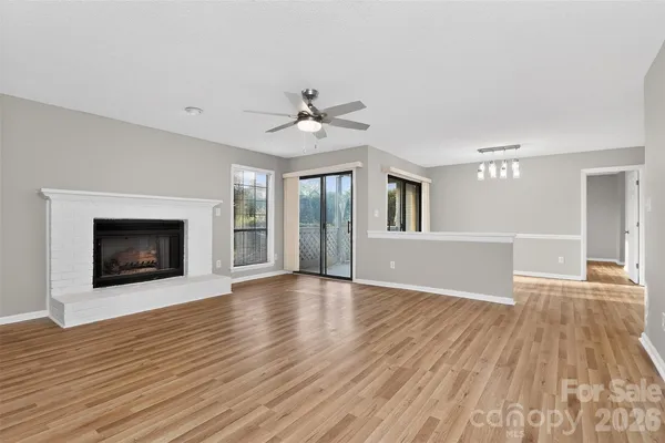 a view of an empty room with wooden floor fireplace and a window