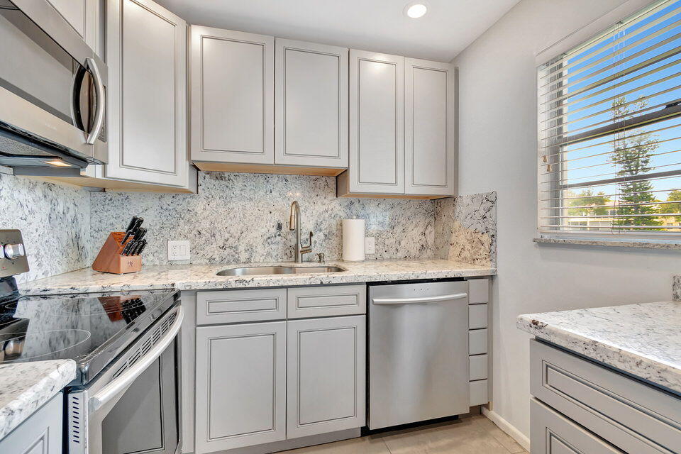 150 Dorset D, Unit 150 Boca Raton, FL 33434 - Photo 18 of 72 a kitchen with granite countertop white cabinets and white appliances