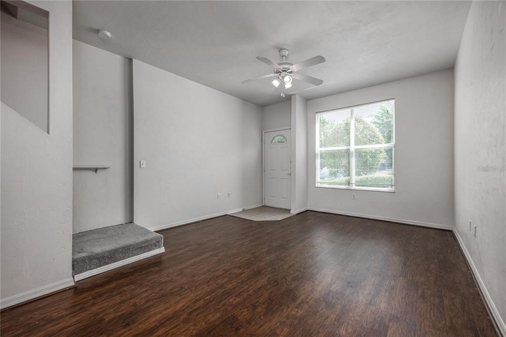 3510 Southwest 30th Way, Unit 158 Gainesville, FL 32608 - Photo 8 of 27 an empty room with wooden floor chandelier fan and windows