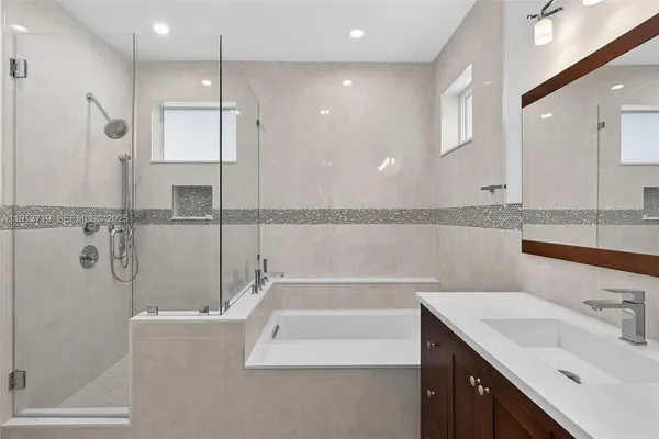 a bathroom with a tub a sink and mirror
