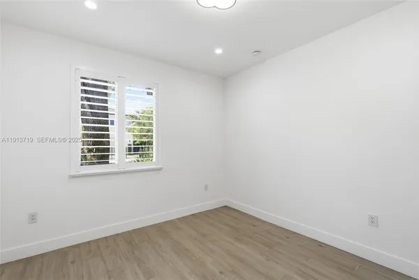 an empty room with wooden floor and a window