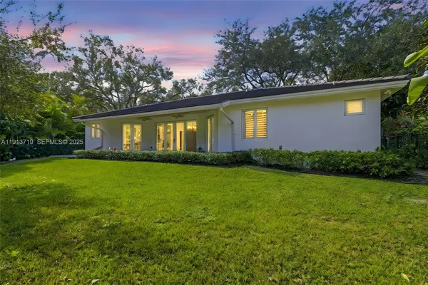 a front view of house with yard and trees in the background