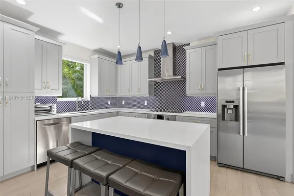 a kitchen with stainless steel appliances a sink a stove a refrigerator and cabinets