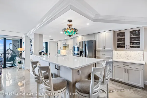 a kitchen with stainless steel appliances kitchen island granite countertop a dining table chairs and a refrigerator