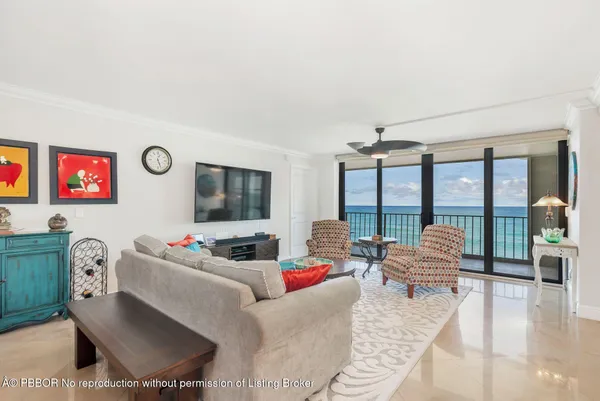 a living room with furniture floor to ceiling window and a flat screen tv