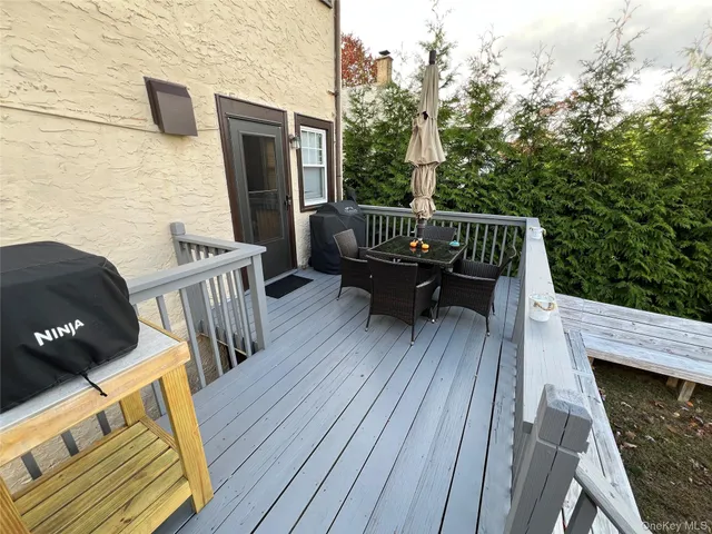 a view of a roof deck with table and chairs with wooden floor and fence
