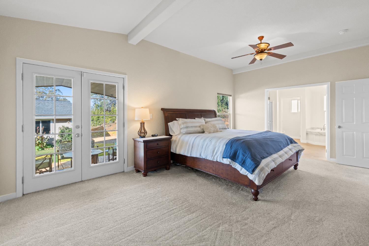 10665 Harris Road Auburn, CA 95603 - Photo 17 of 34 a bedroom with a large bed and a chandelier