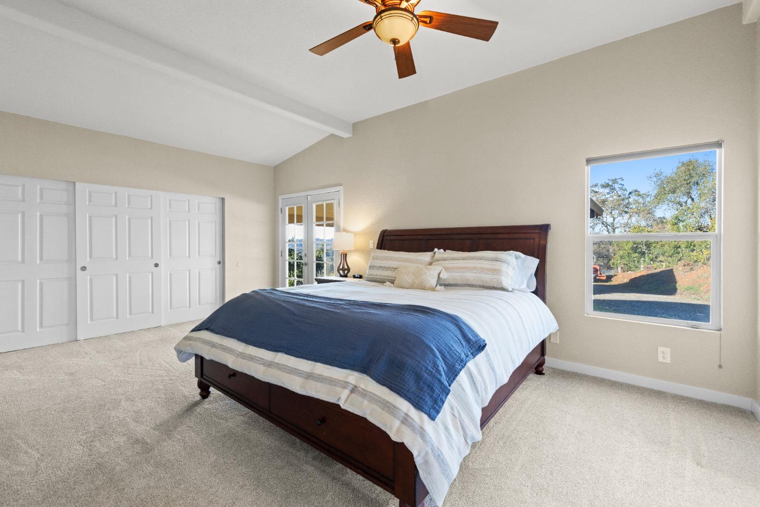 10665 Harris Road Auburn, CA 95603 - Photo 18 of 34 a spacious bedroom with a bed and a chandelier