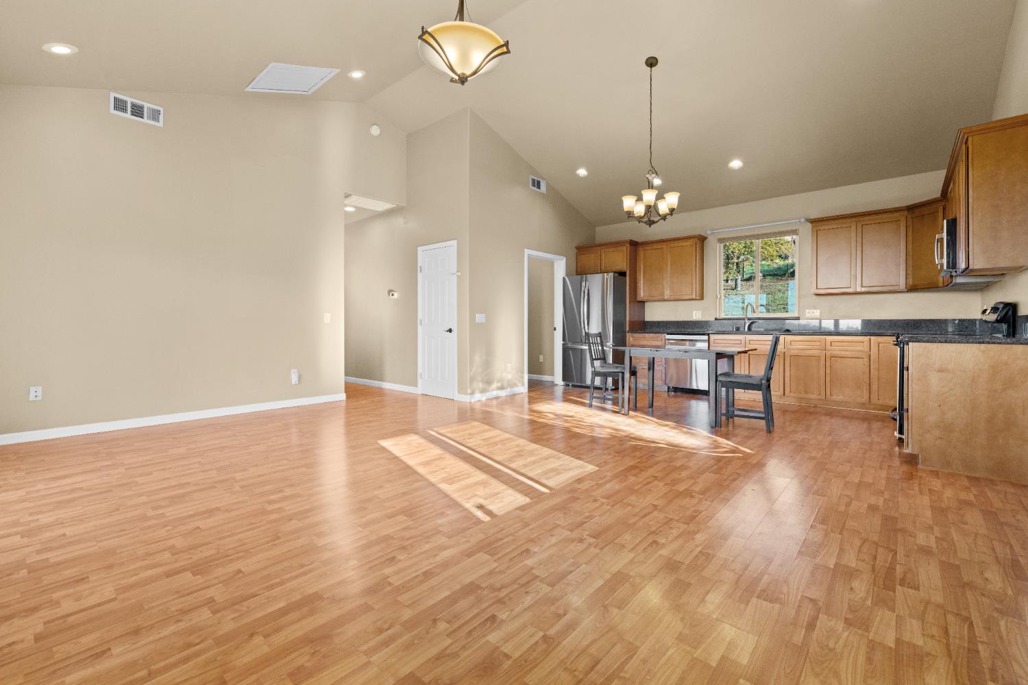 10665 Harris Road Auburn, CA 95603 - Photo 26 of 34 a large kitchen with granite countertop a stove a sink dishwasher a refrigerator and a dining table with wooden floor