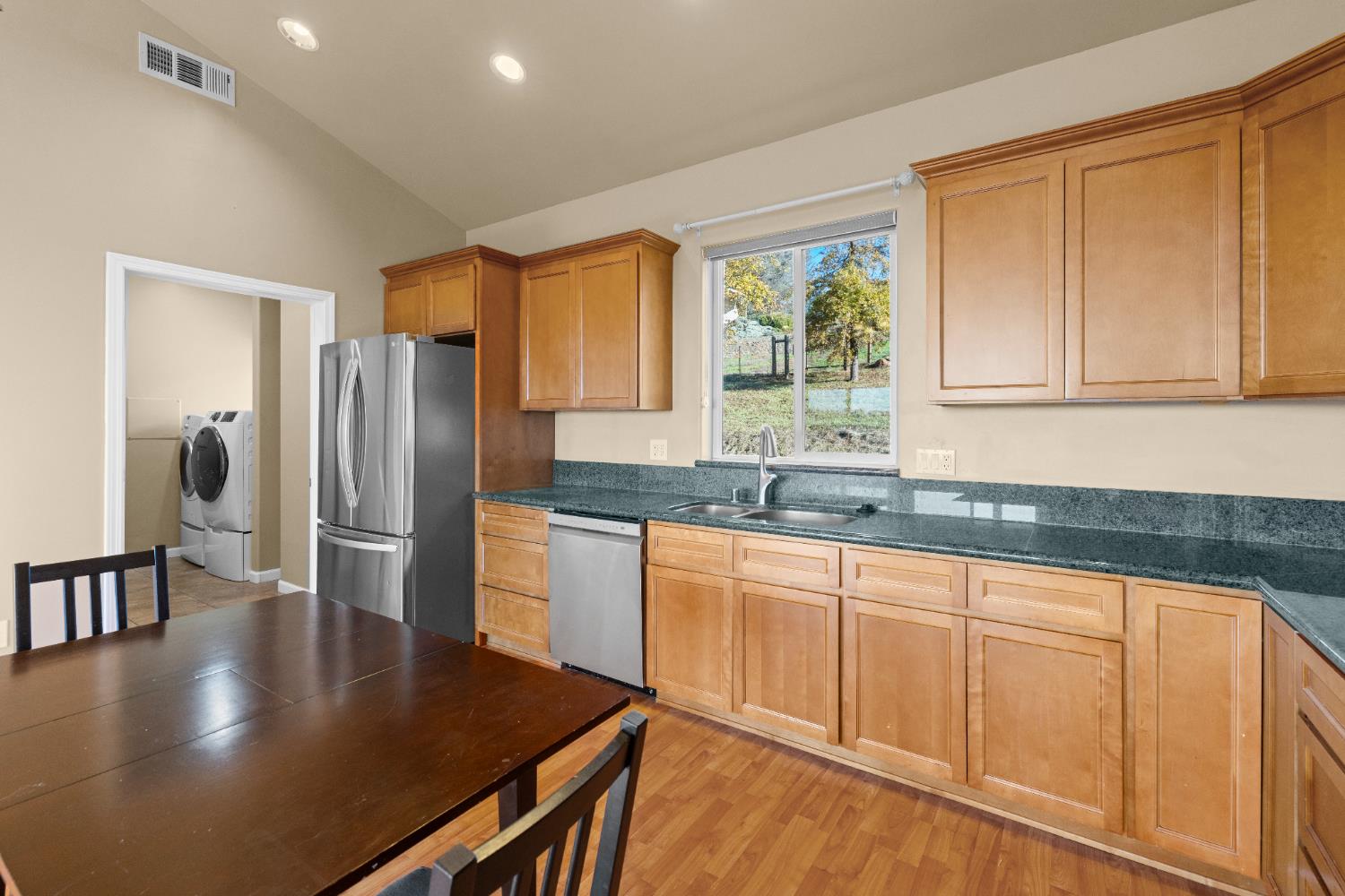 10665 Harris Road Auburn, CA 95603 - Photo 27 of 34 a kitchen with stainless steel appliances granite countertop a refrigerator a sink a stove and white cabinets with wooden floor