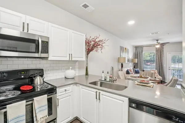 a kitchen with granite countertop a sink stove and microwave