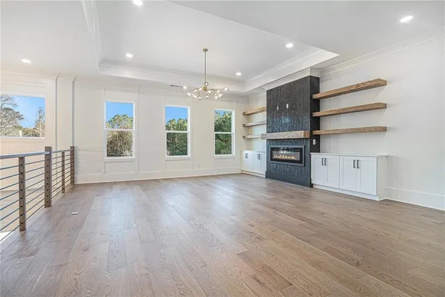 an empty room with wooden floor fireplace and windows