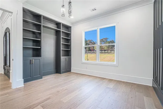 a view of an empty room with a window and wooden floor