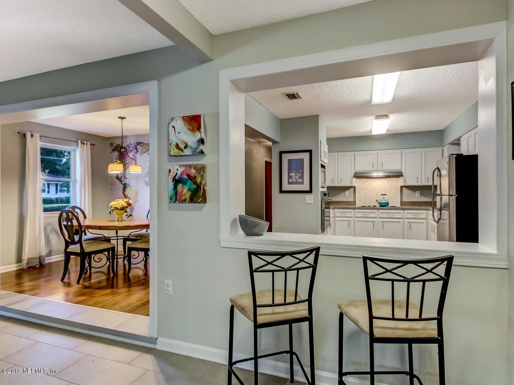 4629 Homestead Road Jacksonville, FL 32210 - Photo 11 of 27 a kitchen with stainless steel appliances kitchen island granite countertop a dining table chairs and a refrigerator