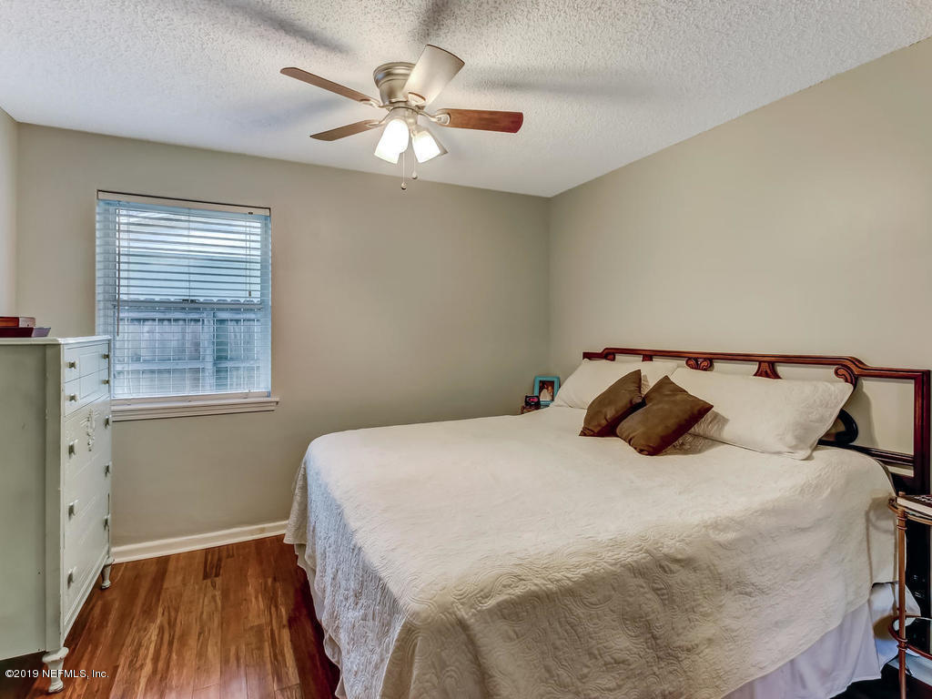 4629 Homestead Road Jacksonville, FL 32210 - Photo 16 of 27 a bedroom with a bed and a chandelier