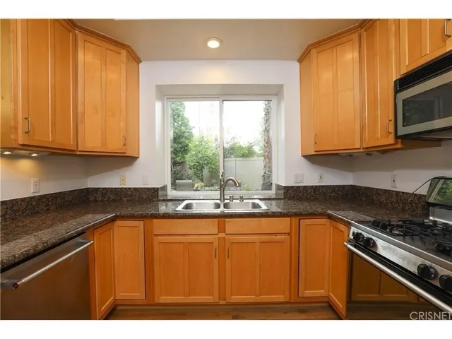 a kitchen with kitchen island granite countertop wooden cabinets a sink and a stove