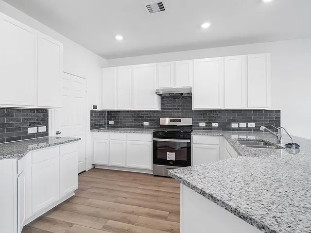a kitchen with stainless steel appliances granite countertop a sink stove and cabinets