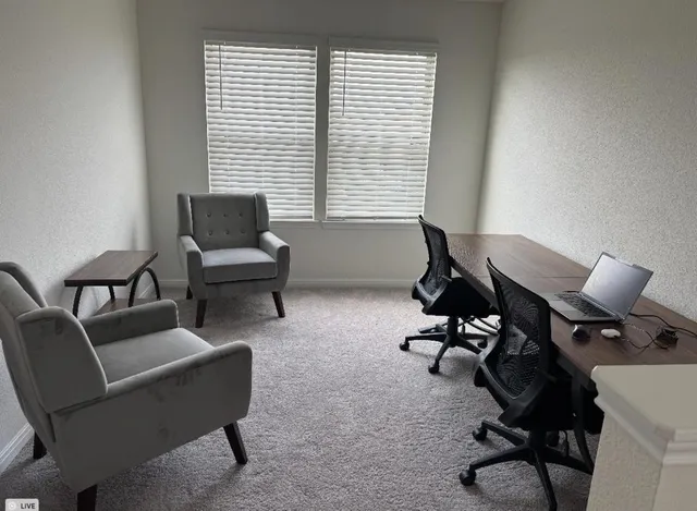 a view of a workspace with furniture and a window