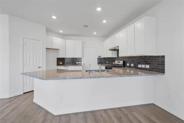 a large kitchen with granite countertop a large counter top and stainless steel appliances