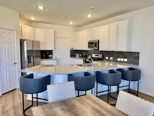 a kitchen with stainless steel appliances kitchen island granite countertop a sink and a refrigerator