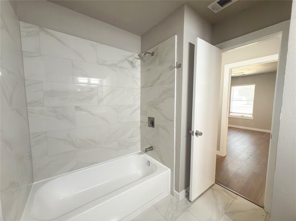 2431 Marfa Avenue Dallas, TX 75216 - Photo 34 of 39 a bathroom with a bathtub and a shower