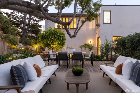 a view of a patio with table and chairs potted plants and large tree